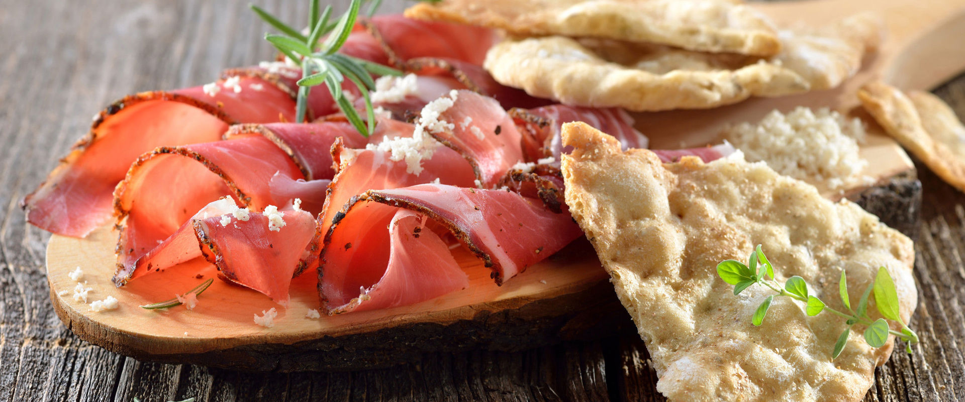 Schüttelbrot Wooden chopping board with bacon, horseradish and Schüttelbrot, a tipical South Tyrolean bread.