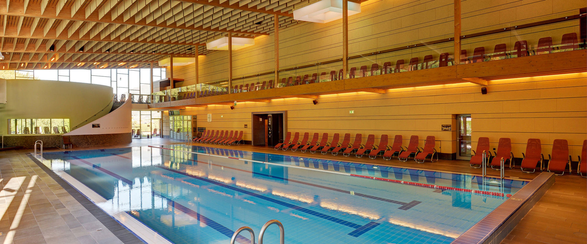 Picture of the indoor swimming pool in Latsch with red deckchairs next to the walls.