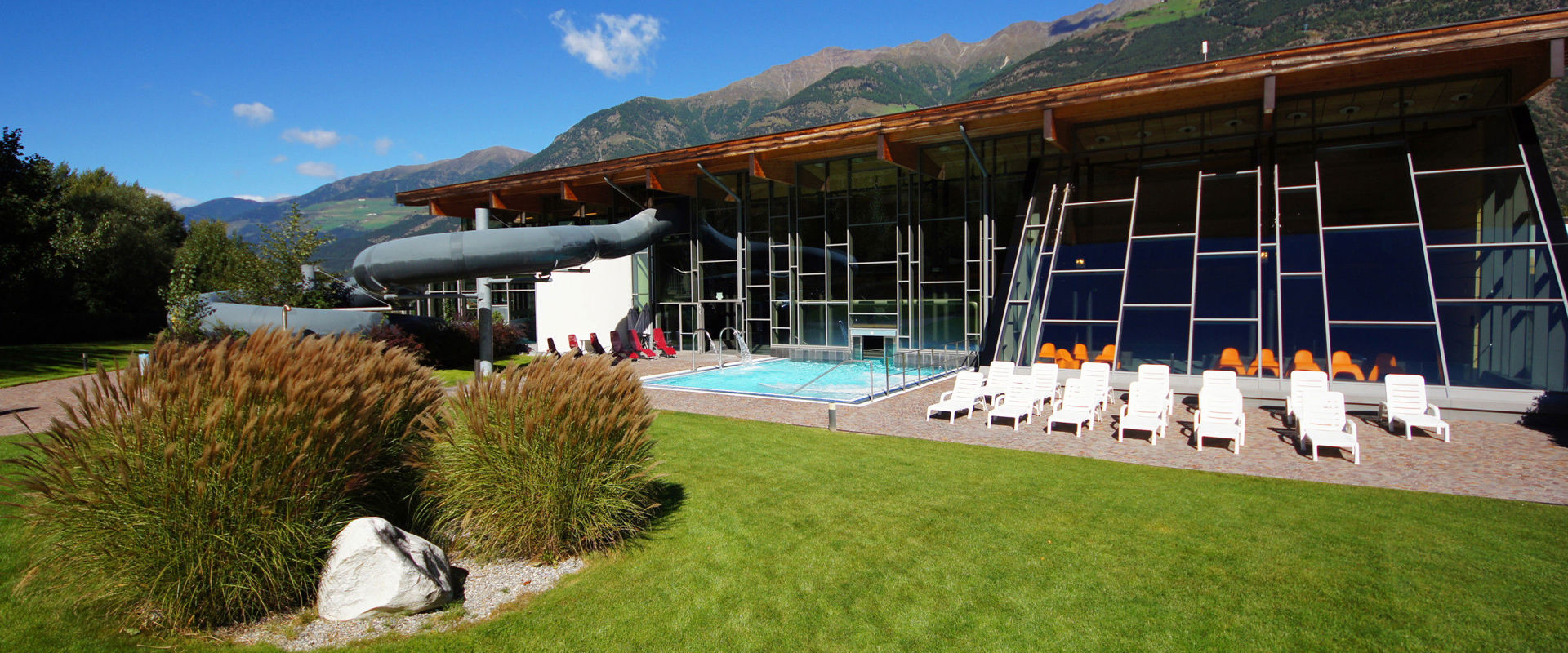 View of the swimming pool in Latsch with sunbathing lawn, slide and outdoor pool.