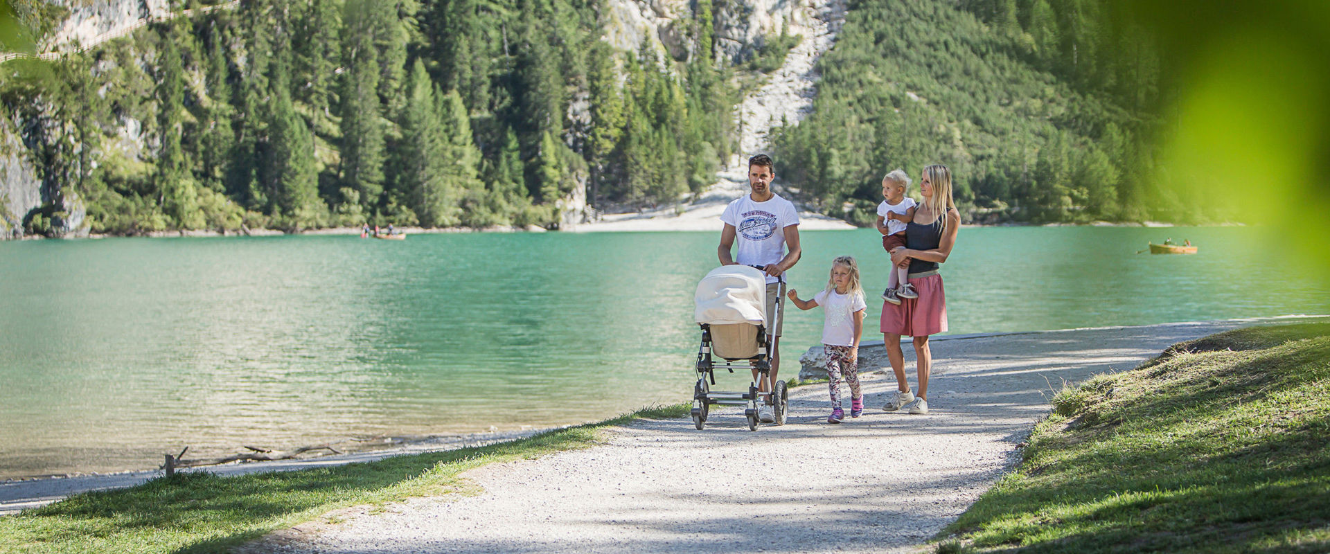 Family of 5 walking along the lakeshore with a pram.