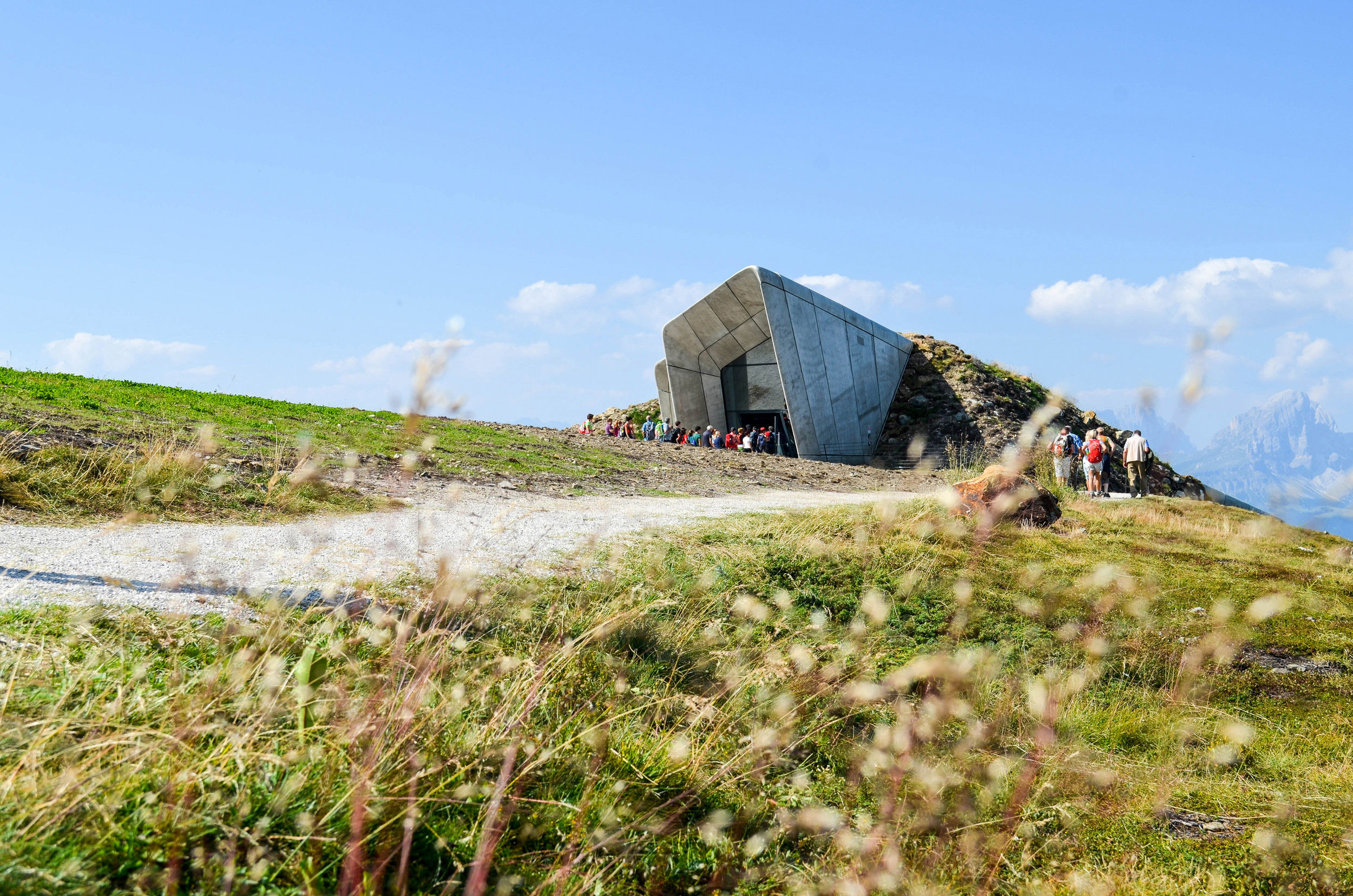 Hikers on their way to the entrance of a museum on a summit plateau.