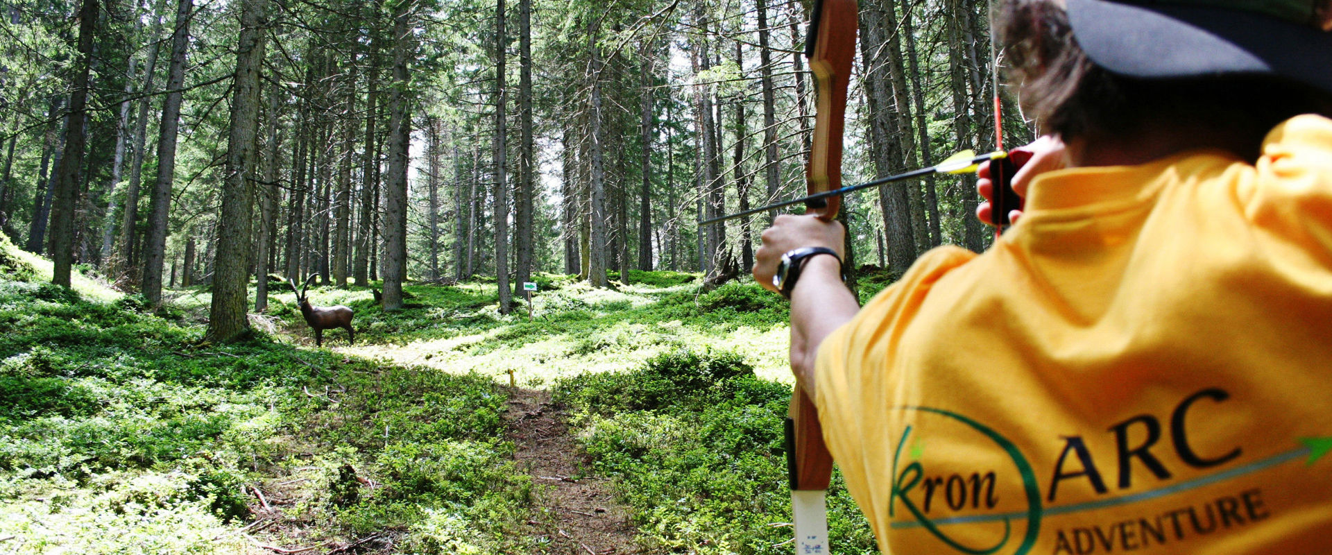 Archery course in Olang. A boy aims at a 3D wooden deer along the archery course in Olang.