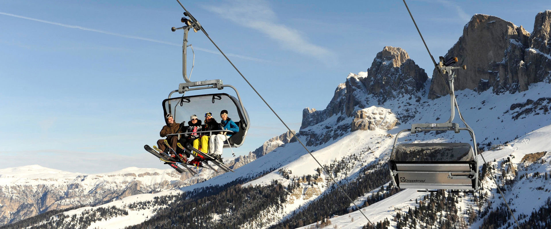 Skiers sitting in the chairlift 4 skiers sitting in the chairlift. In the background you can see the 3 Peaks.