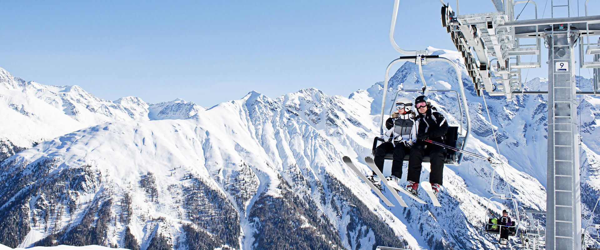 Skiing area Trafoi Skiers sitting in the chairlift.