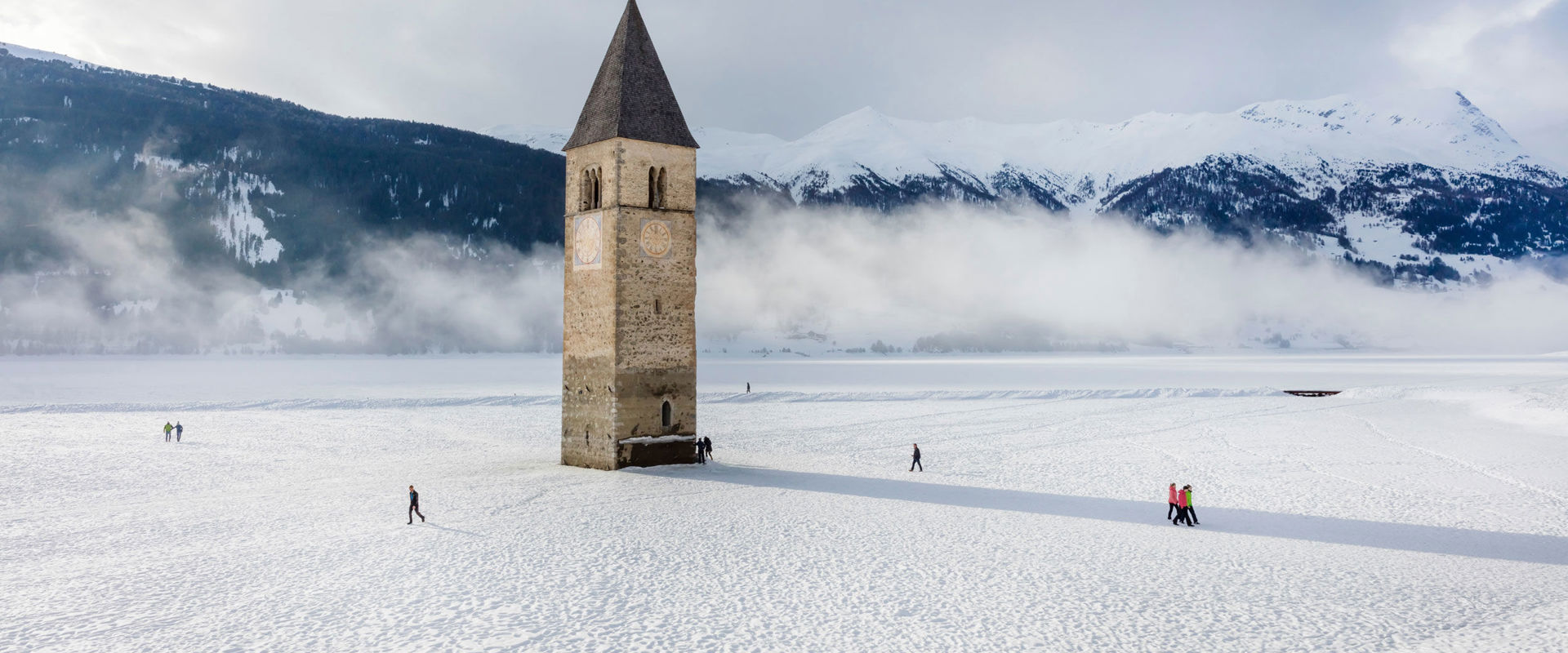 Lake Reschen Snow-covered Lake Reschen with church tower and walkers.
