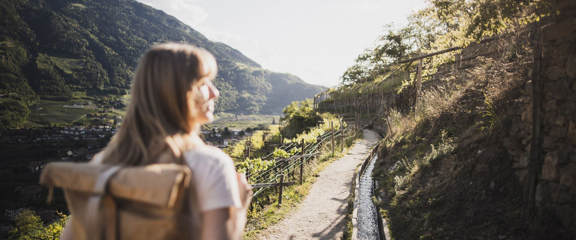 Woman with rucksack hiking along a Waalweg trail