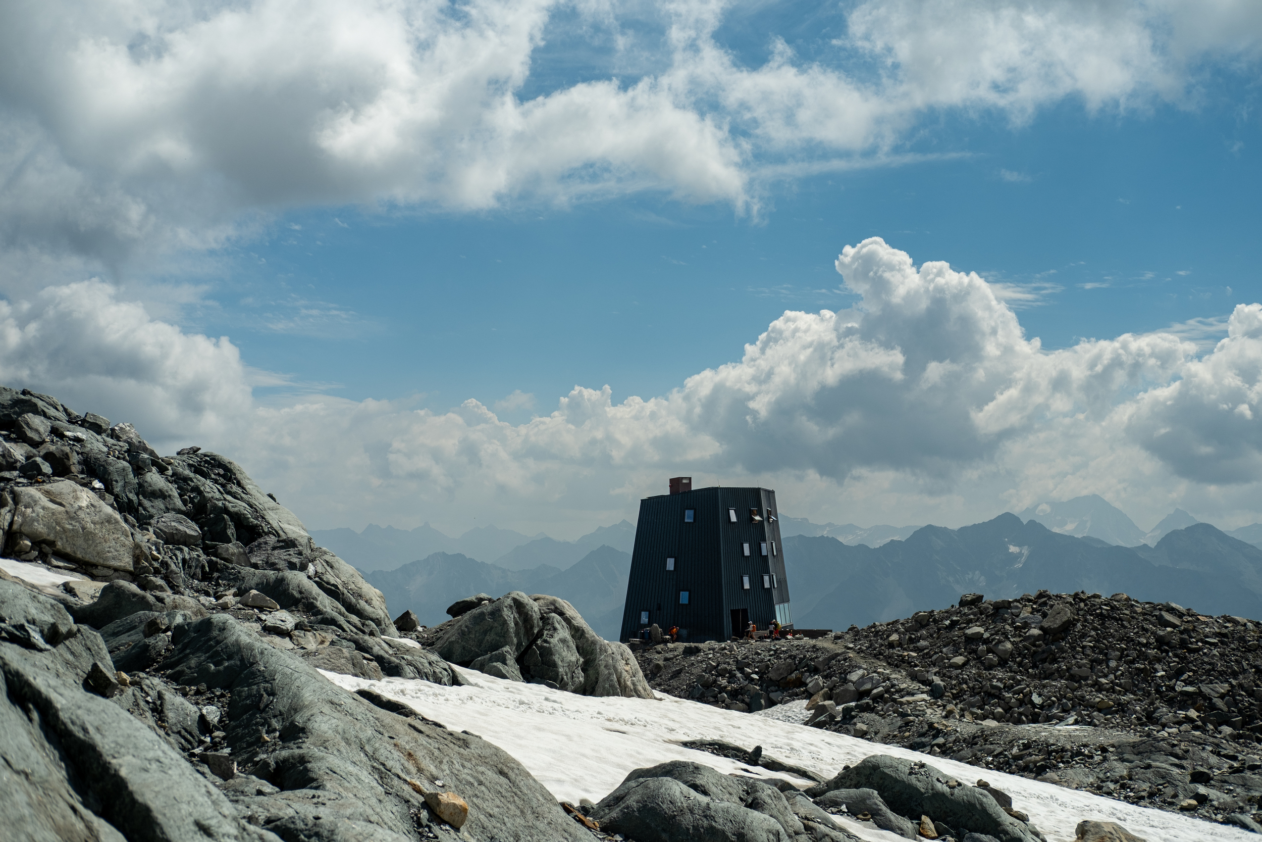 Modern mountain hut in mountain landscape with snowfields