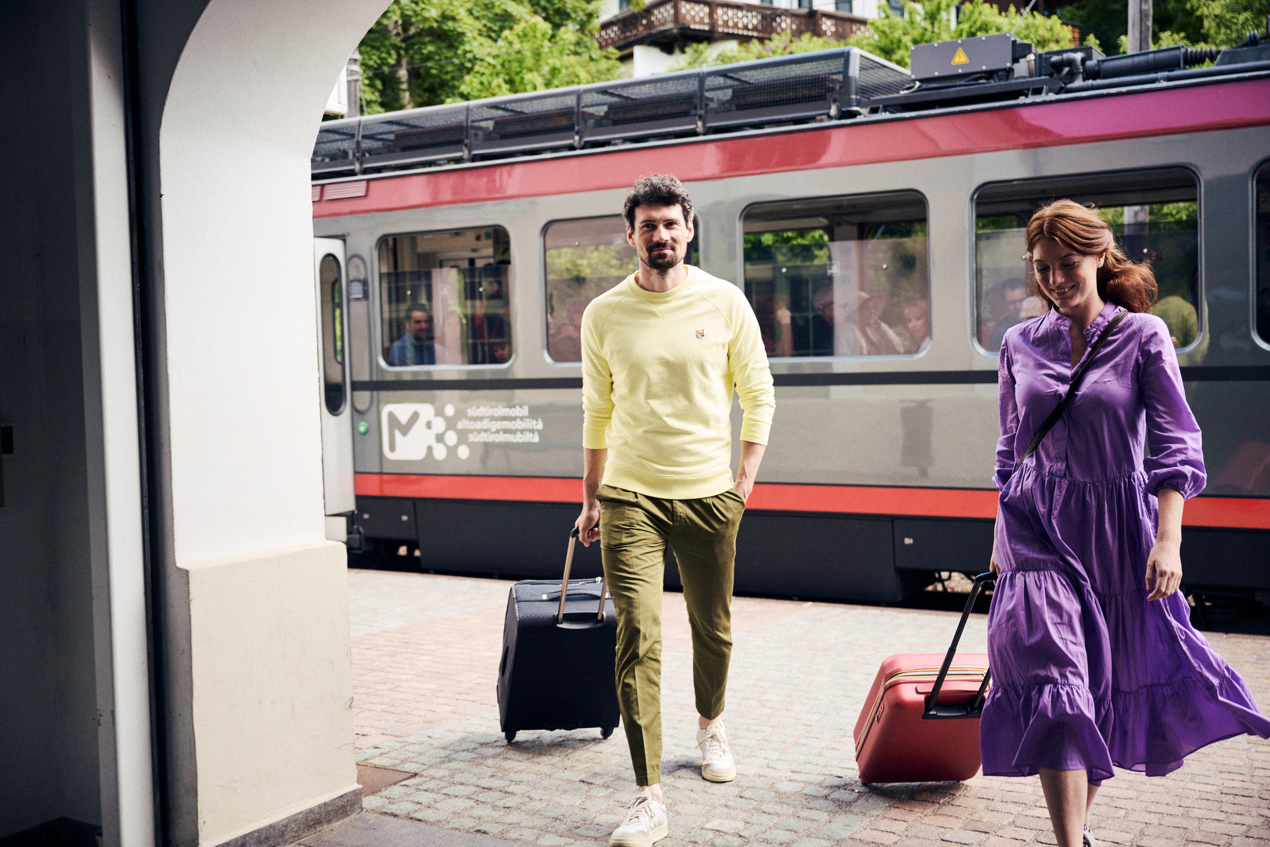 Couple with suitcases at the railway station, with train in the background