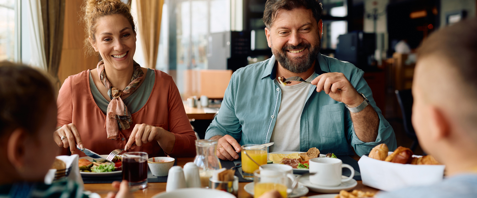 Family meal Family sitting at a table in a hotel, eating breakfast with coffee, bread and waffles