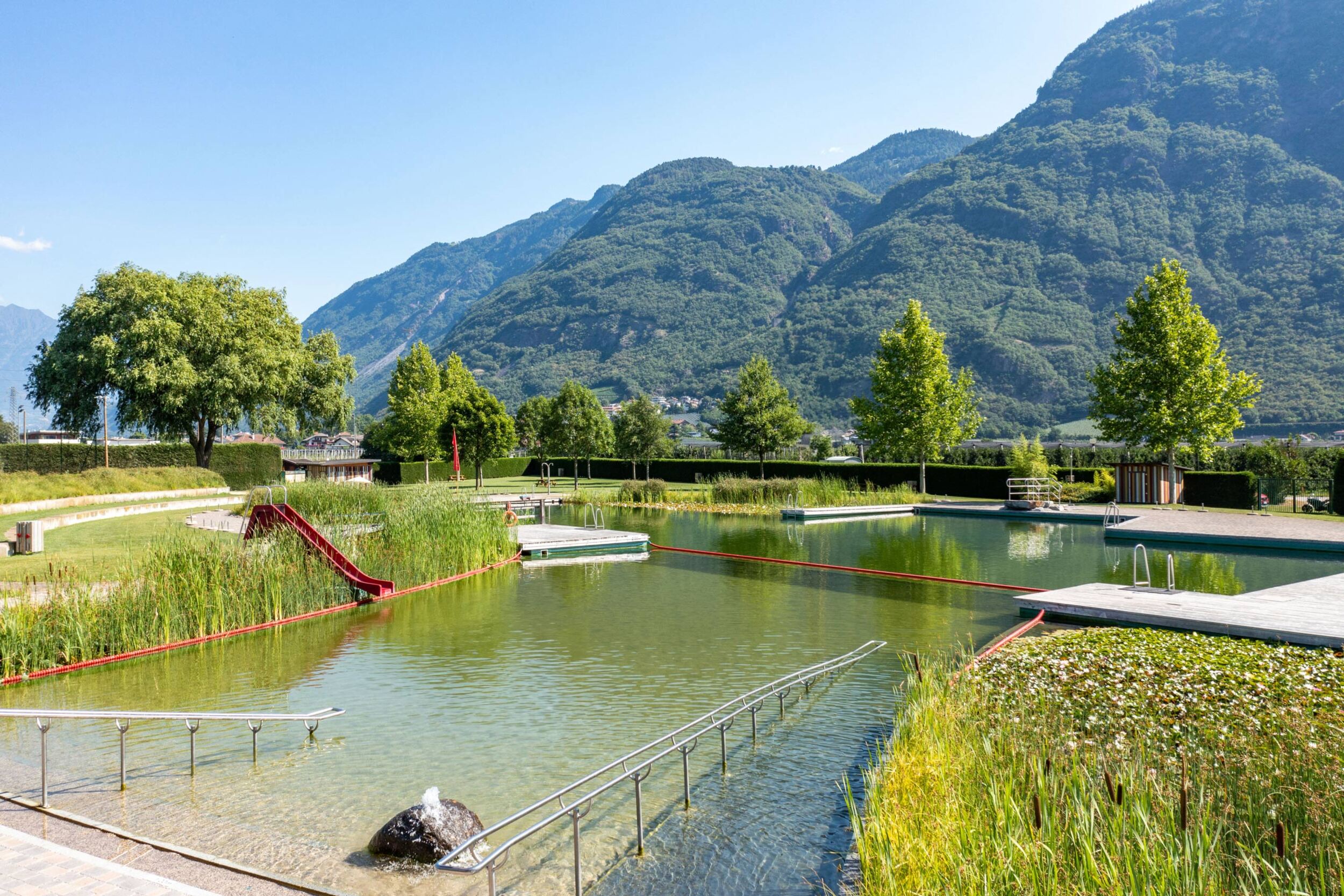 Lake with red slide and sunbathing lawn.