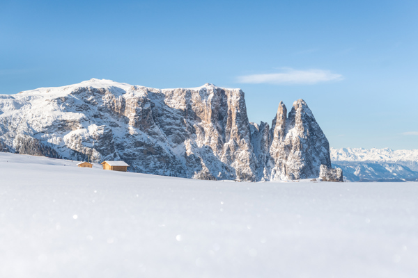 The snow-covered rocky outline of the Schlern against a glistening white snowy landscape