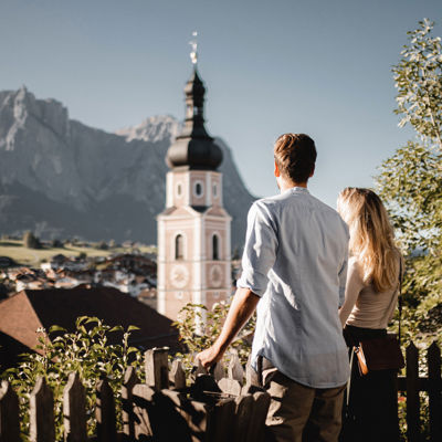 A young couple stands by a wooden fence and enjoys the wonderful view.