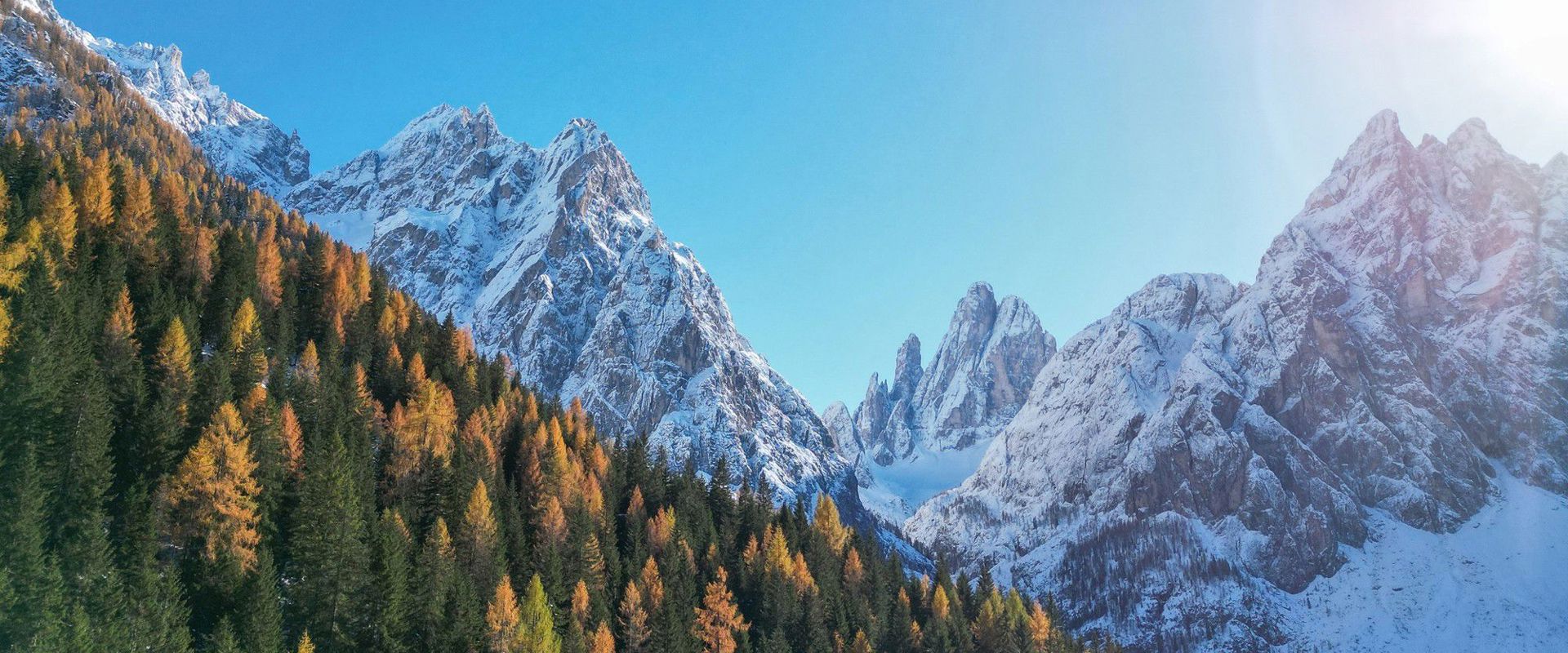 View of the Fischleintal valley with autumnal trees and snow-covered mountains